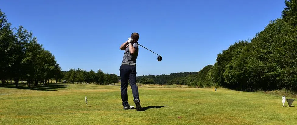 A golfer finishing a drive from the tee